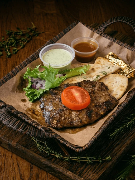 Chapli kabab på fat med nan, salat og to dipp